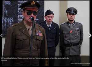 Voják v uniformě SS u pamětní desky příslušníků RAF